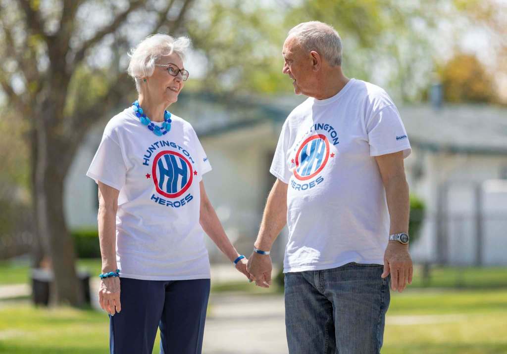 SASHA SEFTER / WINNIPEG FREE PRESS President of the local chapter of the Huntington Society of Canada Vern Barrett (right) and his wife Ellen who lives with Huntington disease walk through their neighbourhood. Both are wearing white tshirts sporting the Huntington Heroes logo. They are holding hands and looking into each others eyes.